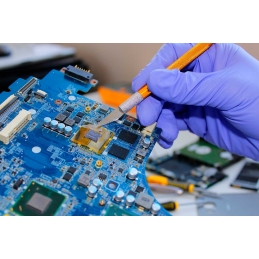 Mainboard visibile e strumenti per la riparazione come cacciaviti e multimetro accanto.